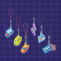 Godliath 1-inch acrylic Alt Mode phone charms featuring colorful Transformers vehicle designs on a grid background.