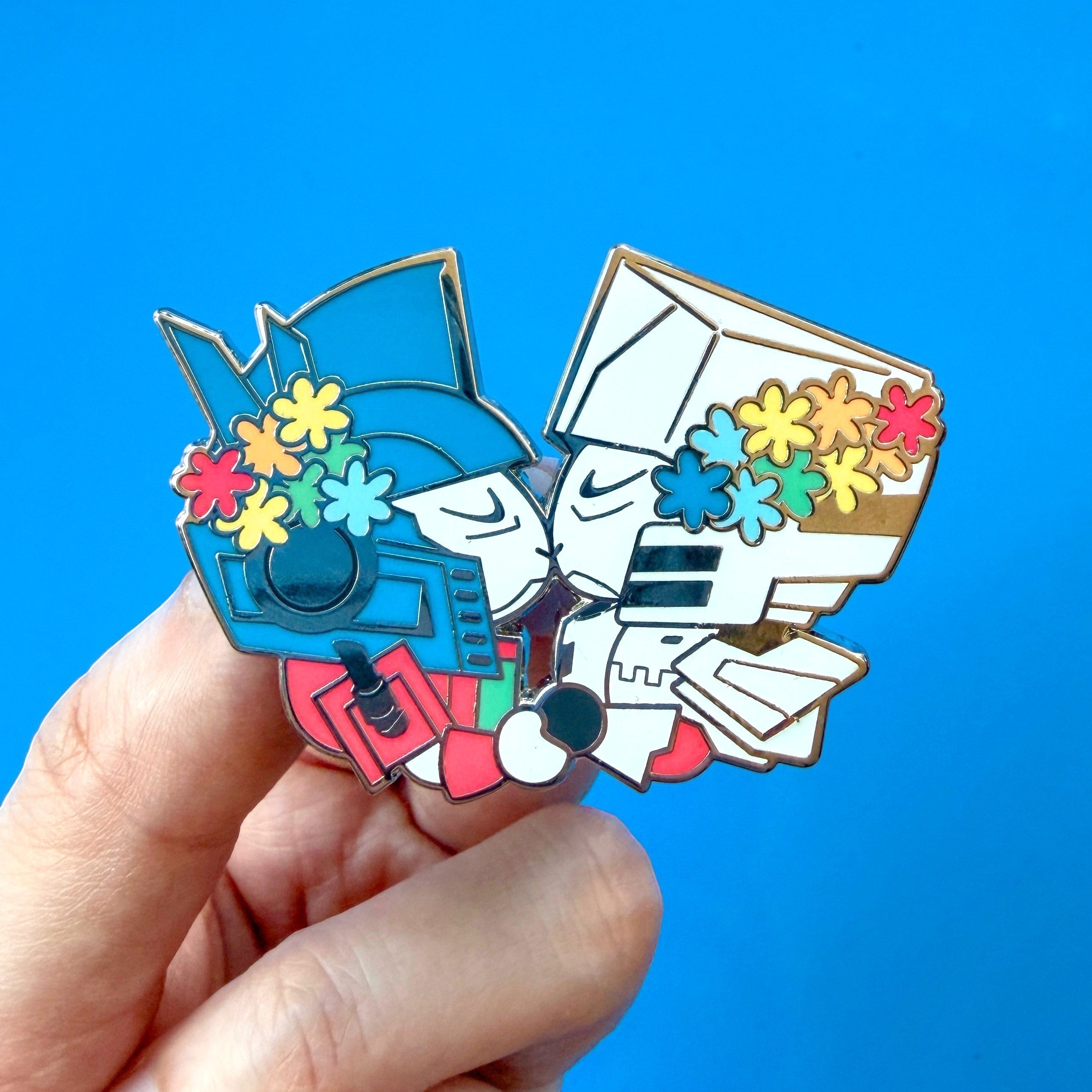 Godliath Tinybots ES MegOp 2-inch silver hard enamel pin featuring two kissing robot grandpas with colorful flowers.