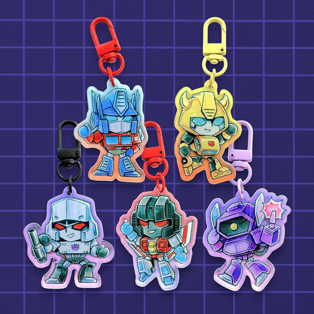 Godliath Transformers G1 acrylic keychains featuring Optimus Prime, Megatron, Bumblebee, Starscream, Shockwave with a translucent gradient effect.